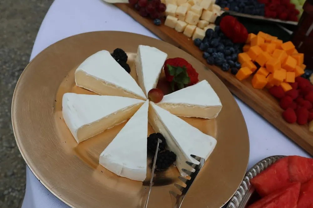 Brie wheel with berries on a cheese and fruit board