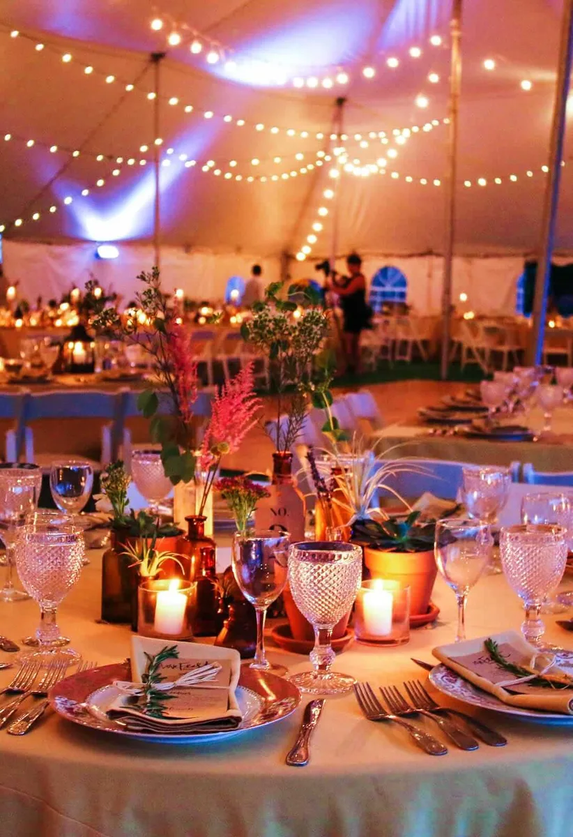 Candlelit reception tables under string lights in the tent